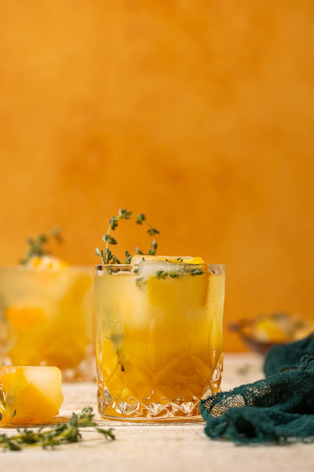 Two glasses of mocktails with an orange background.