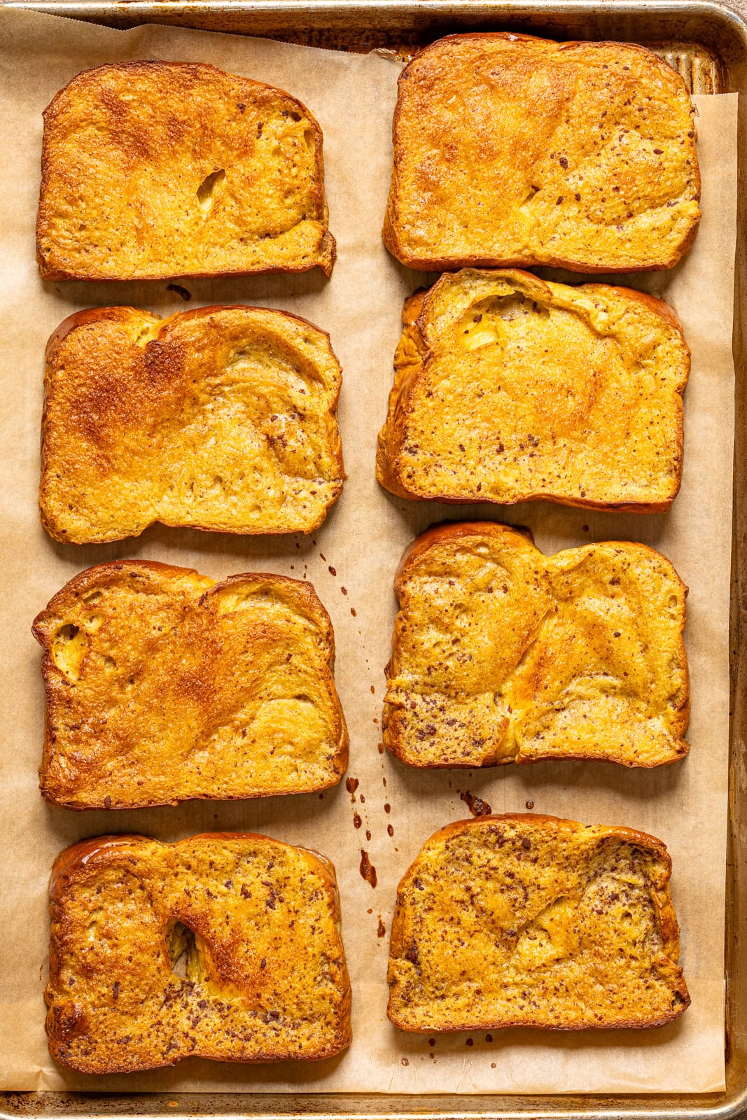 Baked french toast lined on a baking sheet with parchment paper.