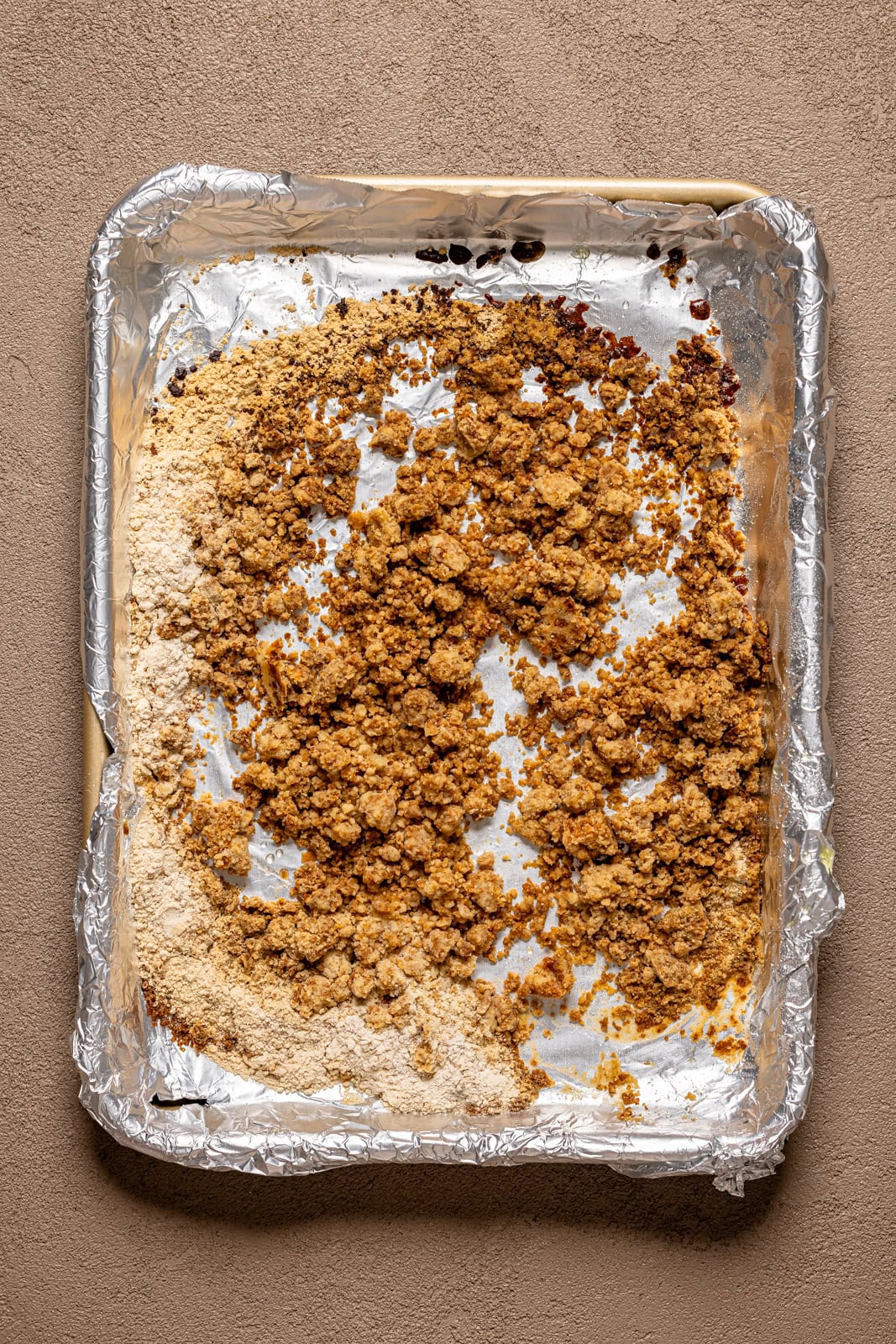 Crumble topping on a baking sheet with foil paper.