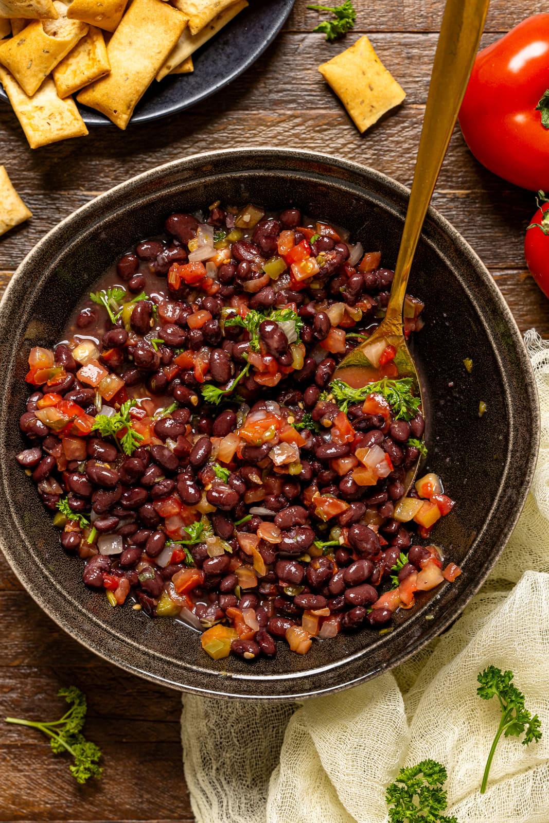 Black bean salad in a bowl with a gold spoon.