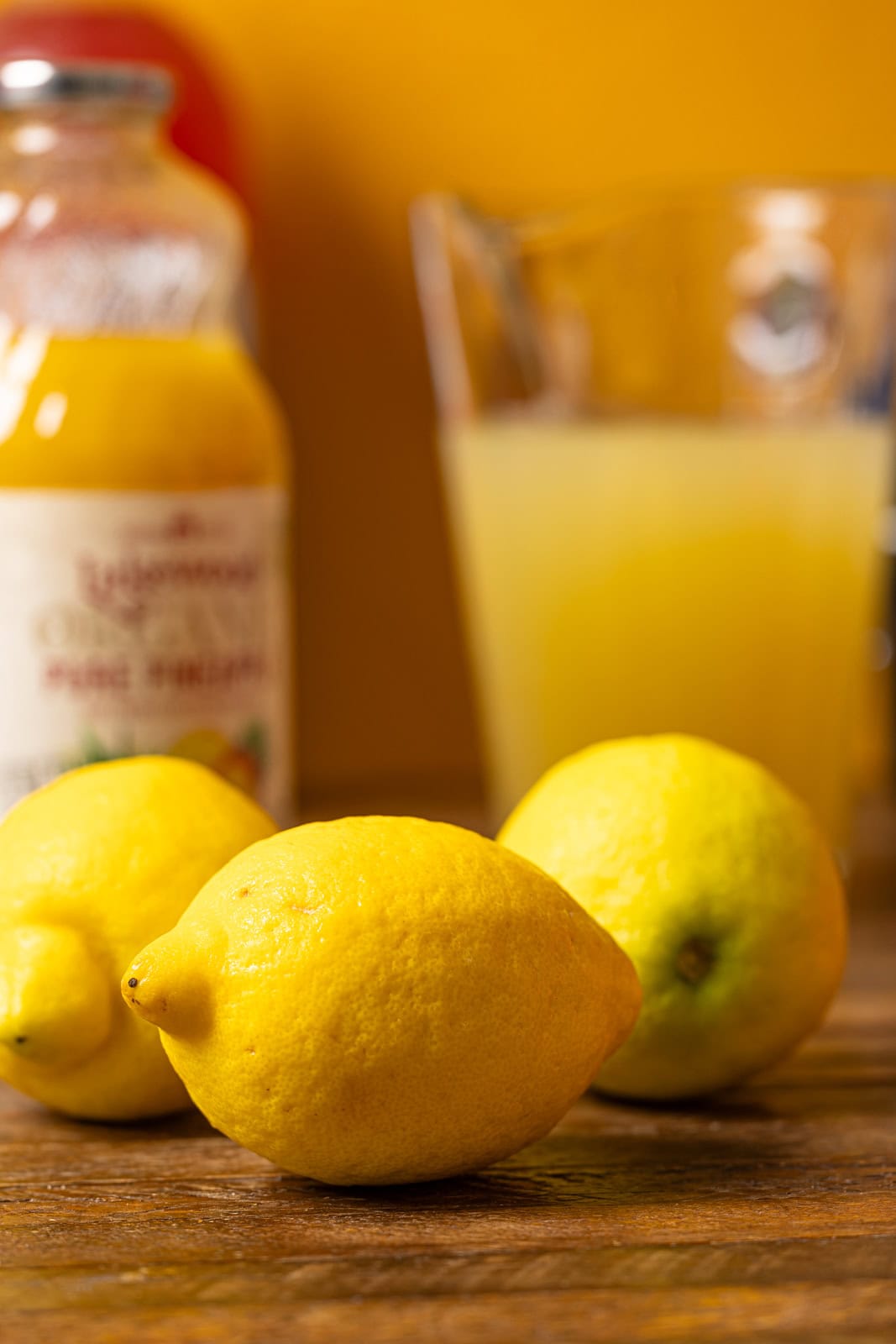 Lemons and juice on a brown wood table.
