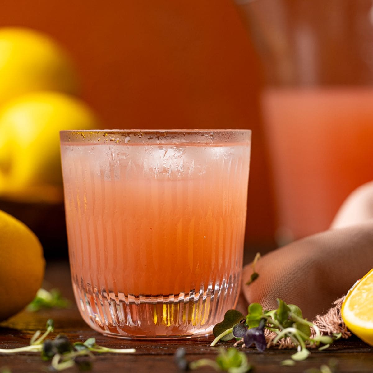 Up close shot of pink lemonade in a glass with lemons.