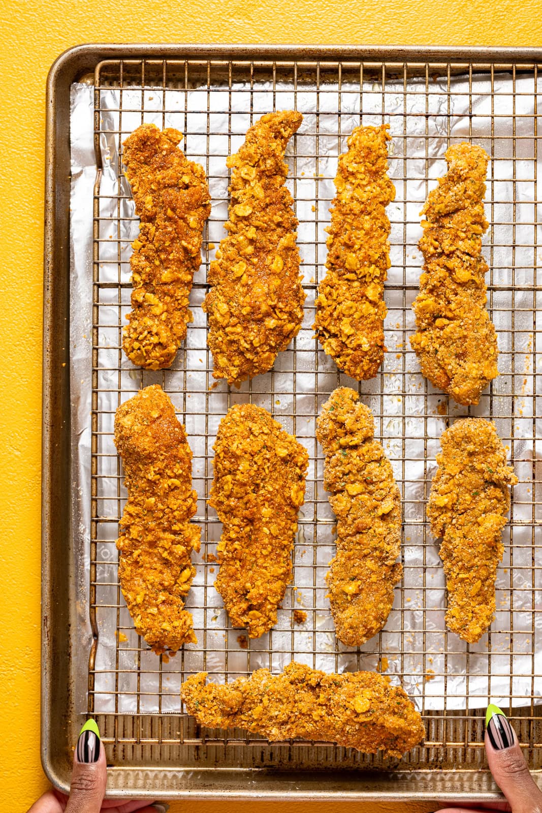 Chicken tenders lined on a baking sheet with wire rack.
