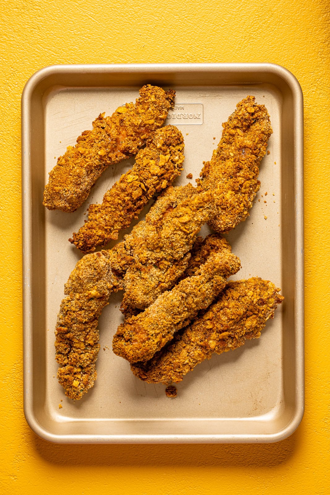 Baked chicken tenders on a baking sheet.