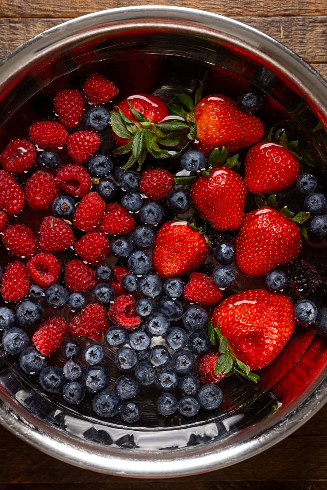 Fresh berries being soaked in a bowl with water.