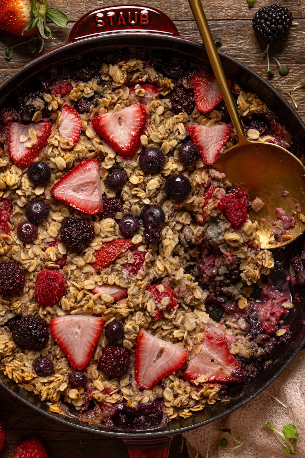 Up close shot of baked oatmeal in a skillet with a gold spoon.