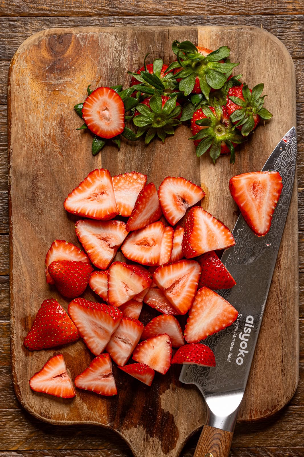 Sliced strawberries on a cutting board with a knife.