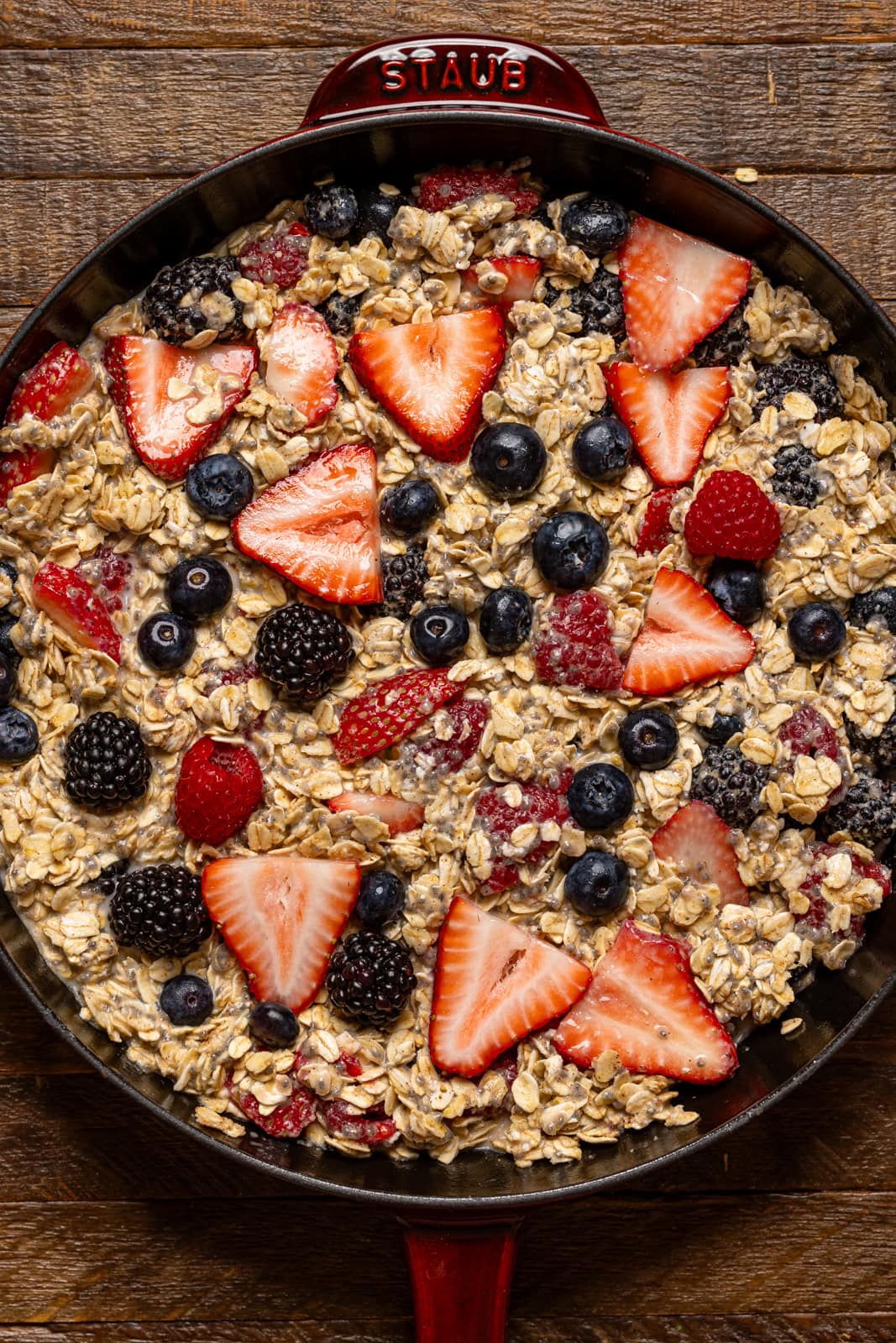 Baked oatmeal ingredients in a burgundy skillet.