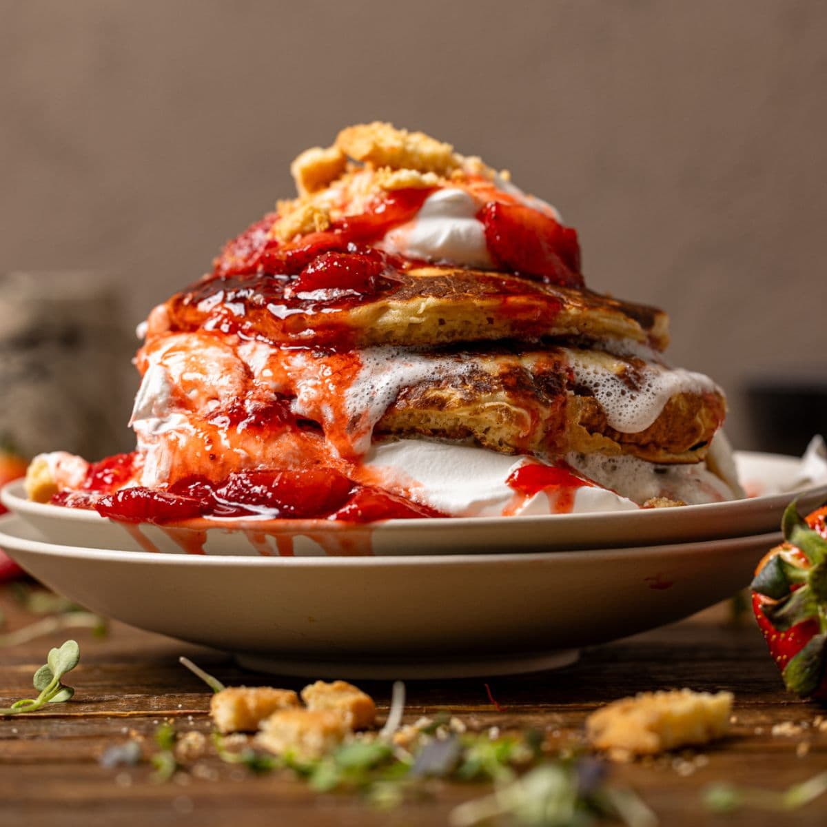Stacks of pancakes with whipped cream, strawberries, and cookies.