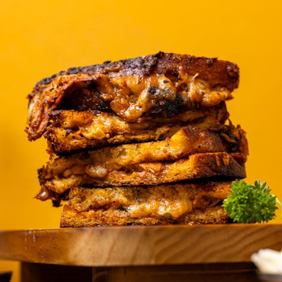 Stack of grilled cheese with a yellow background.