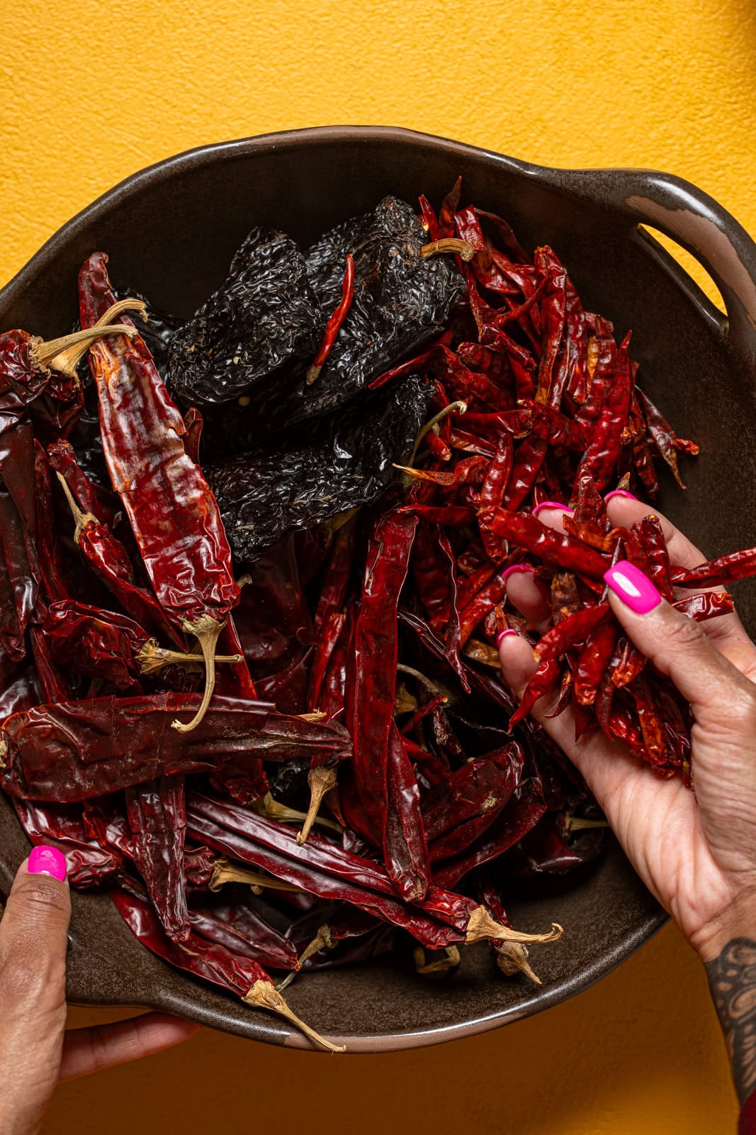 Bowl full of peppers being held.