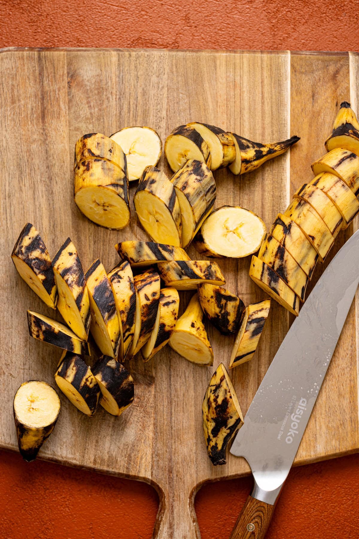 Chopped plantain on a cutting board with a knife.