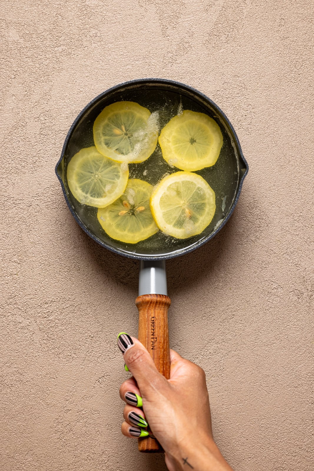 Lemon simple syrup being held in a pot.