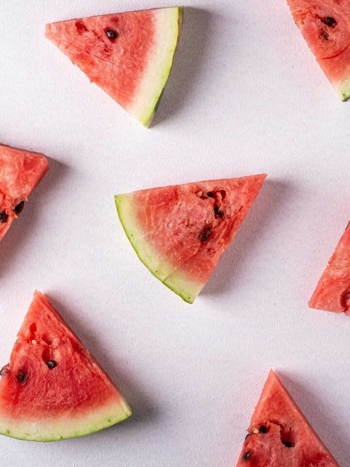 Watermelon cut into wedges on pink background.
