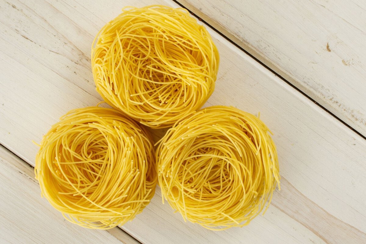 Angel hair pasta on a white wood table.