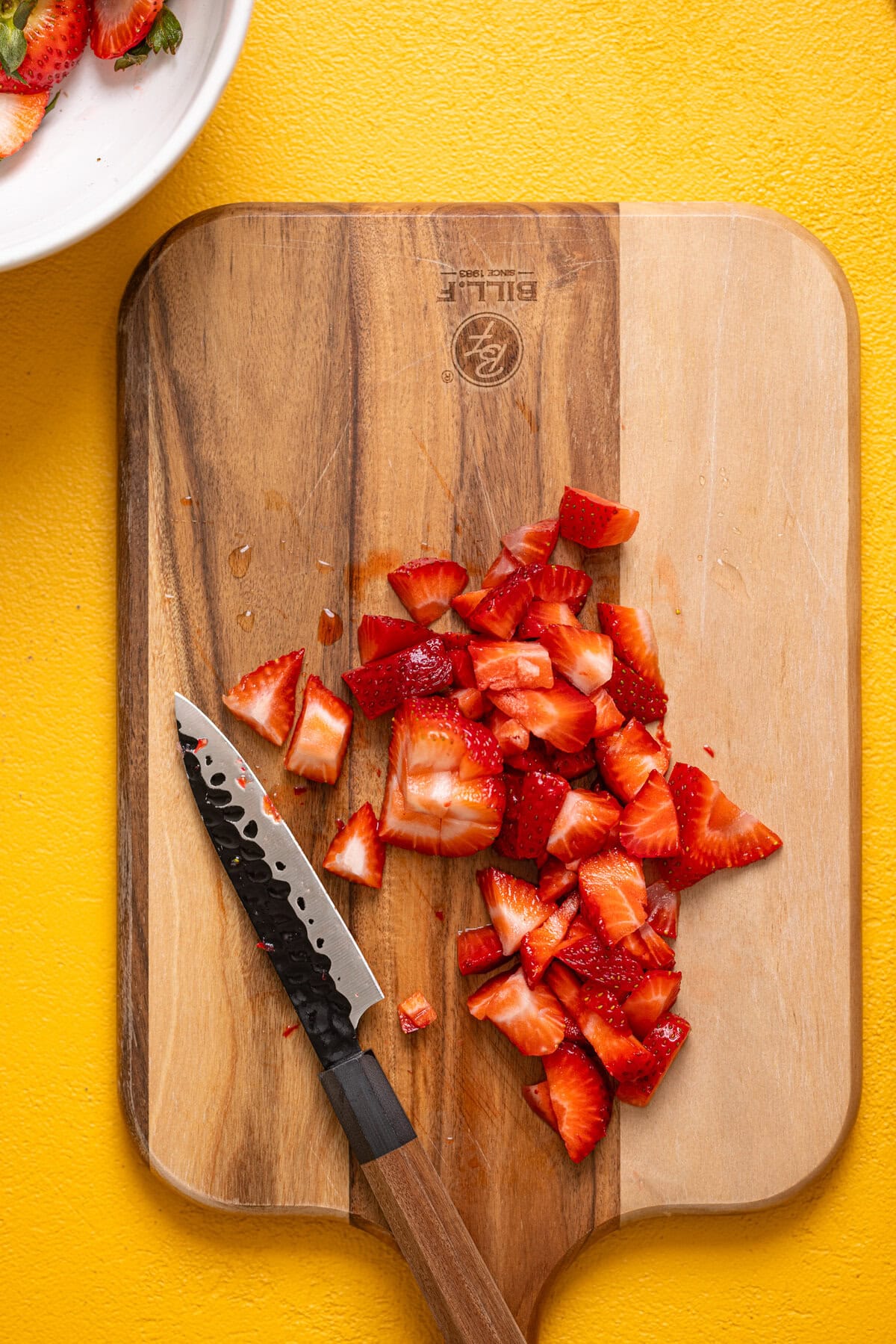 Diced strawberries on a cutting board with a knife.