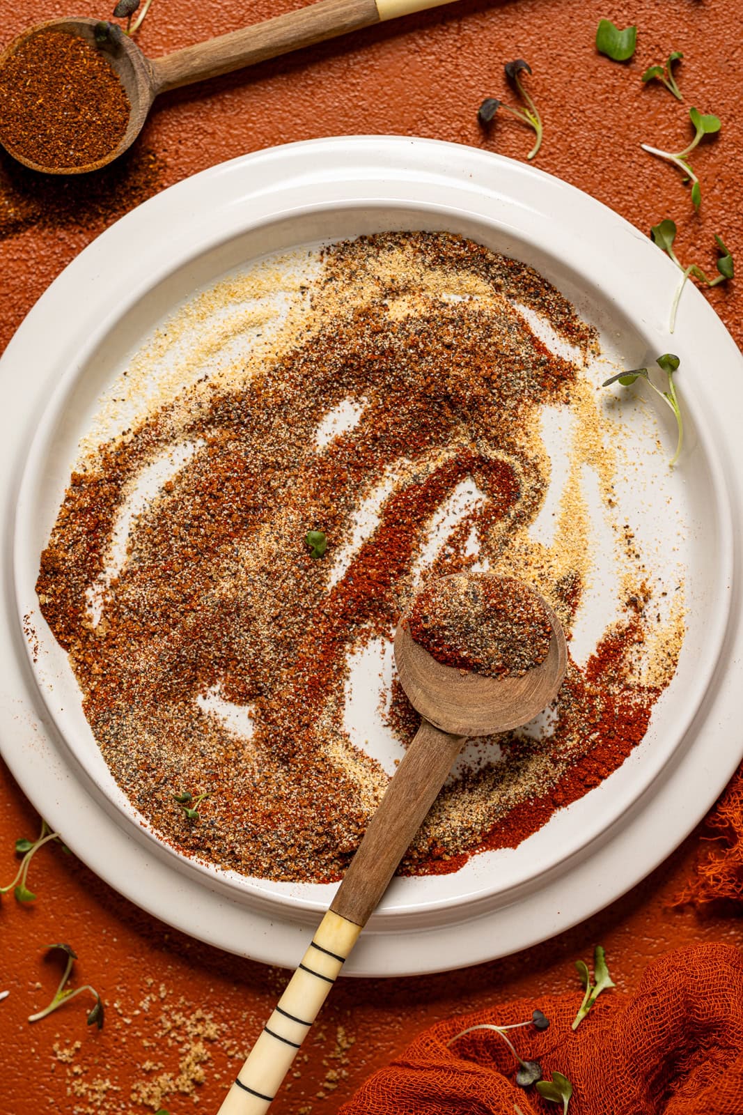 Up close shot of seasoning on a white plate with two spoons.