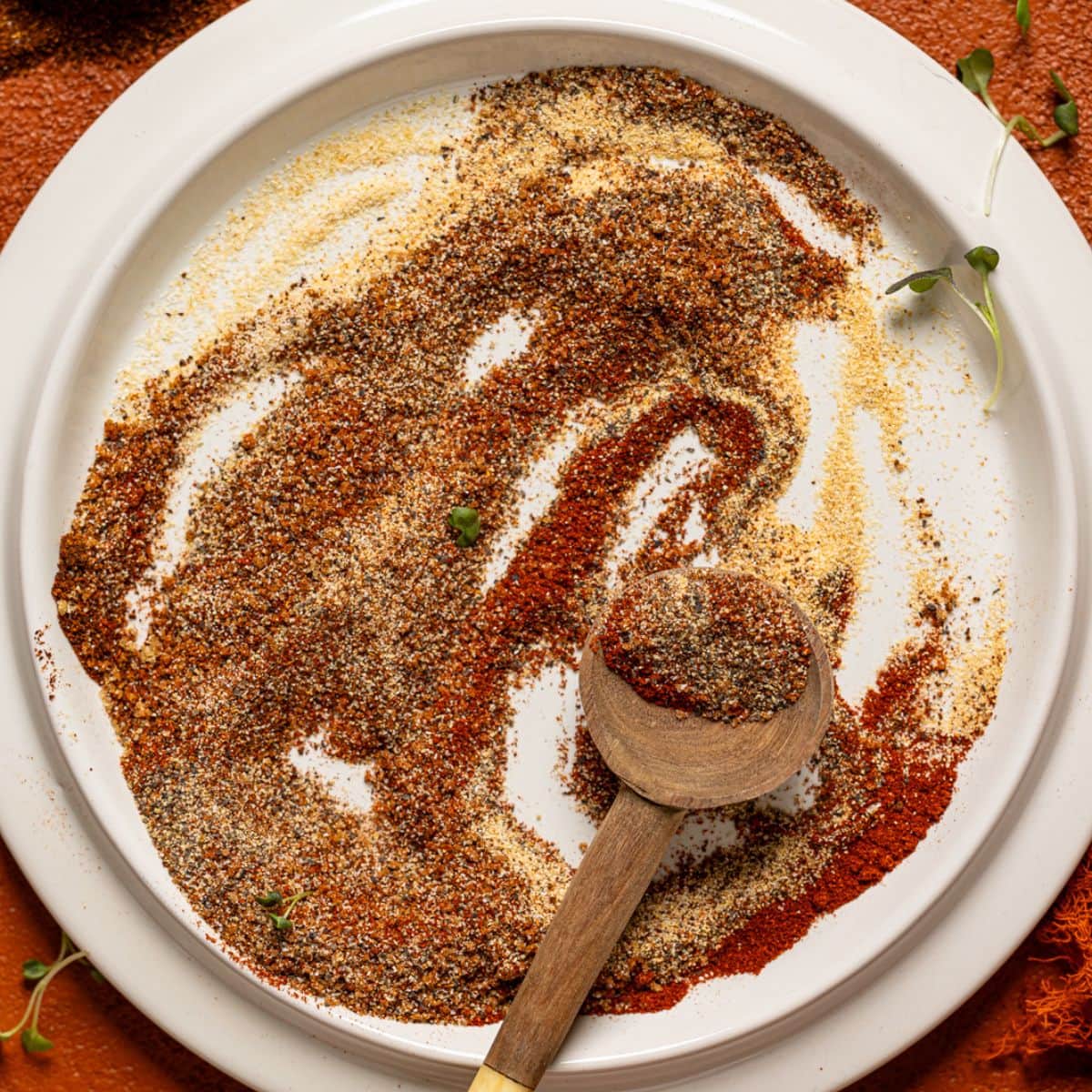 Up close shot of seasoning on a white plate with two spoons.