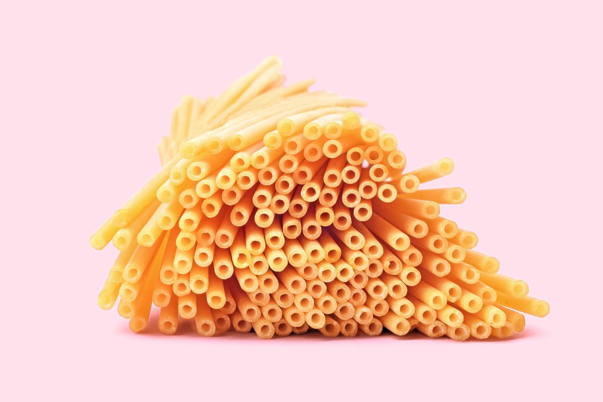 Bucatini pasta with pink background.