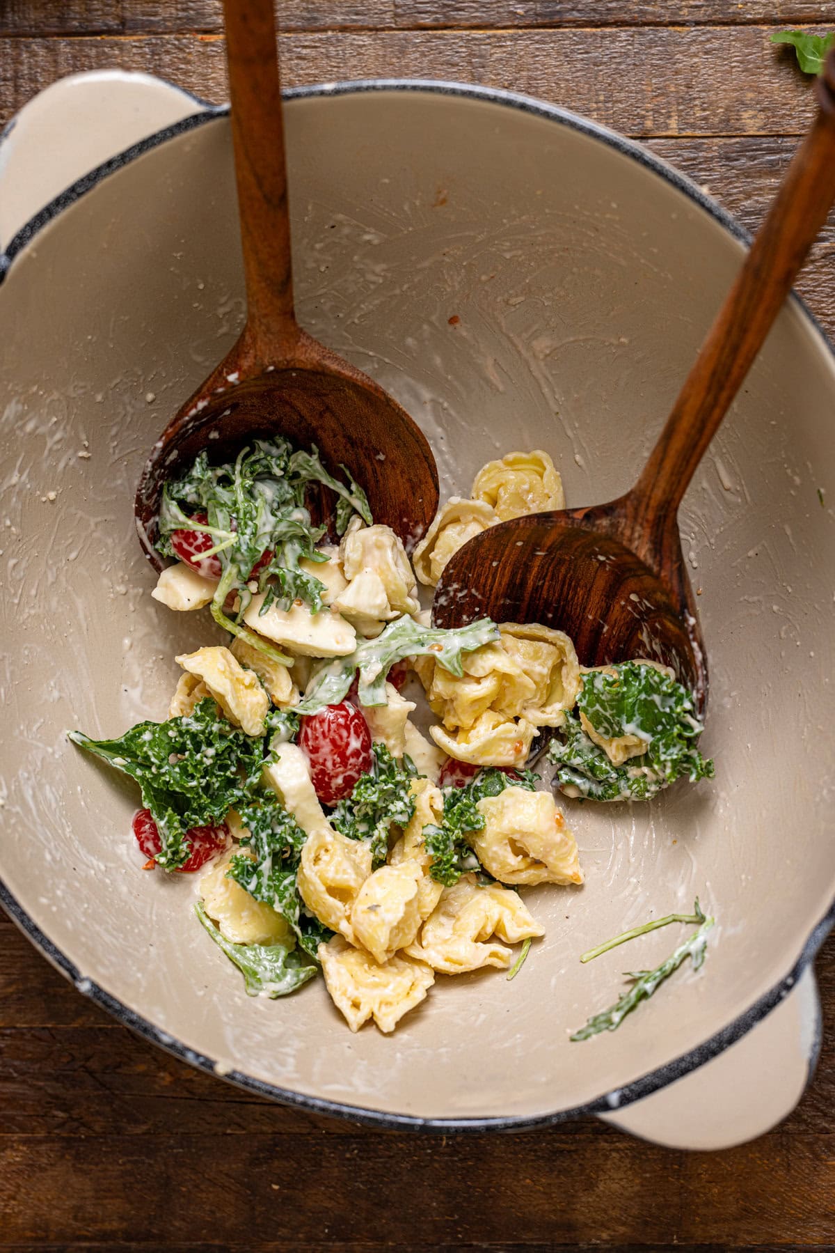 Bowl with remaining pasta salad and wooden serving spoons.