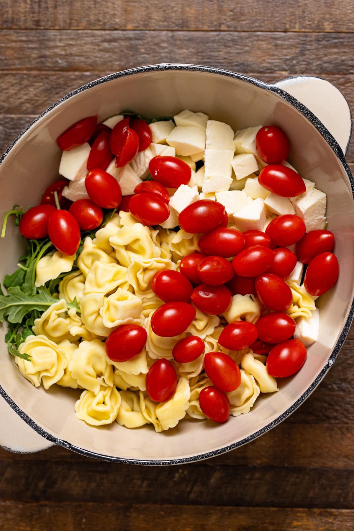 Salad ingredients in a bowl on a brown wood table.