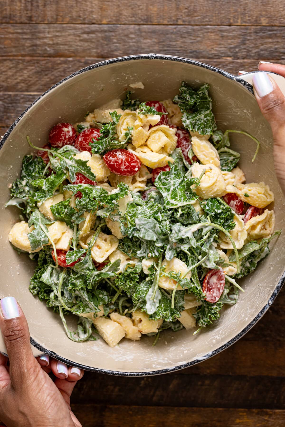 Pasta ingredients mixed together and being held in a bowl.