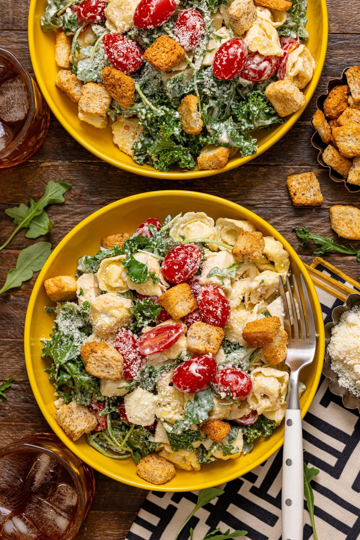 Two bowls of pasta salad with a fork and a drink.