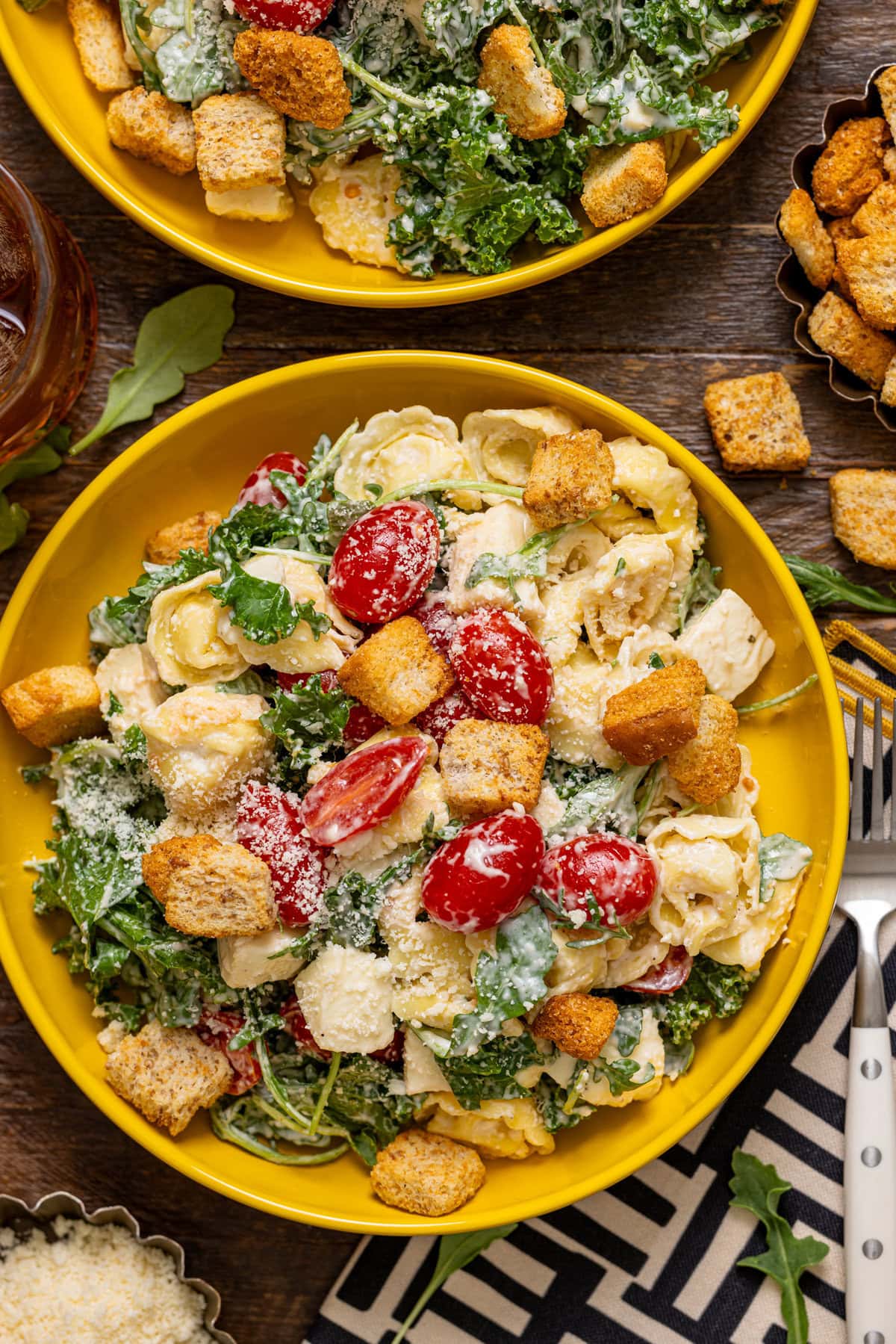 Pasta salad in a bowl with a drink and croutons.