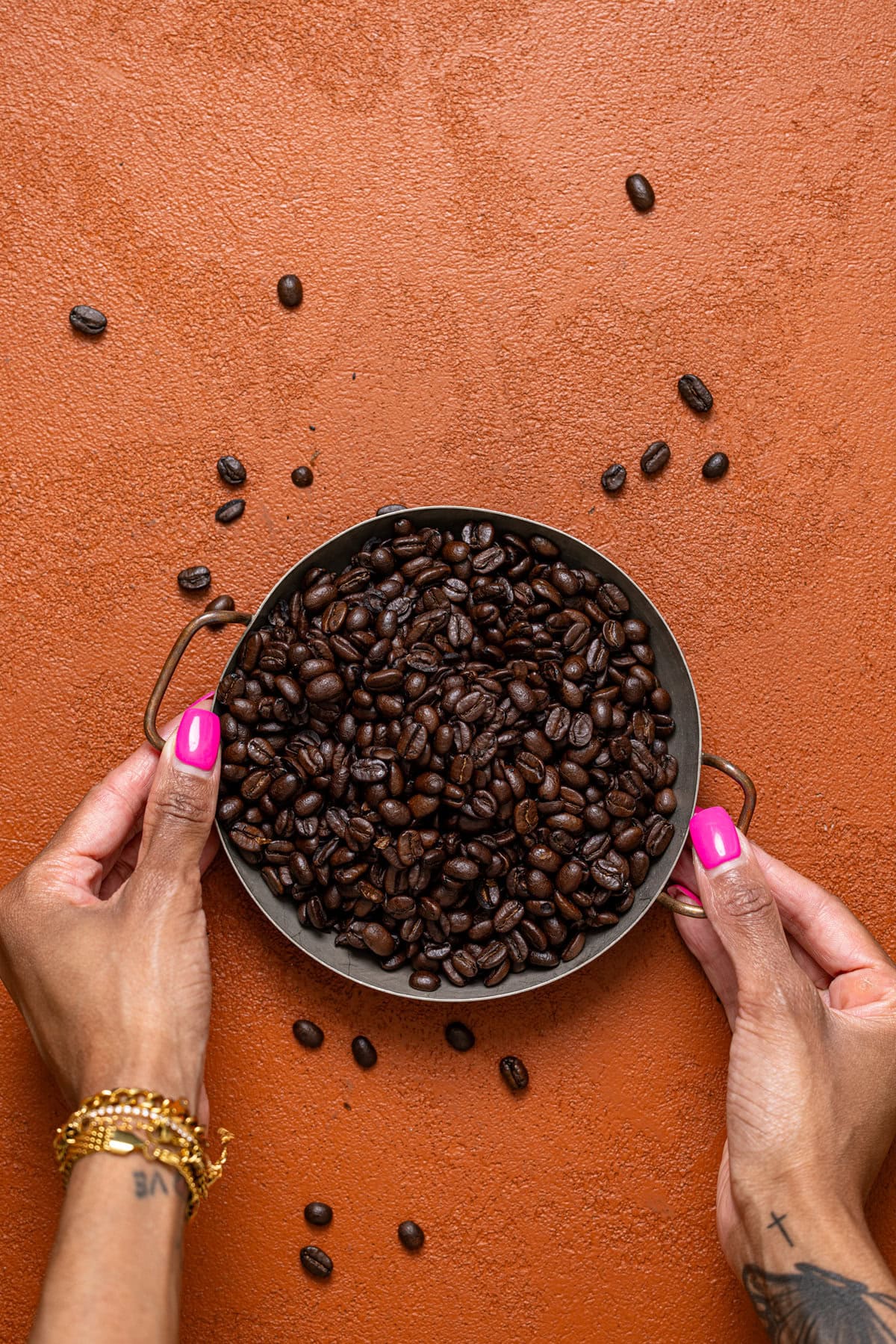 A tray of espresso beans being held on a burnt orange table. 