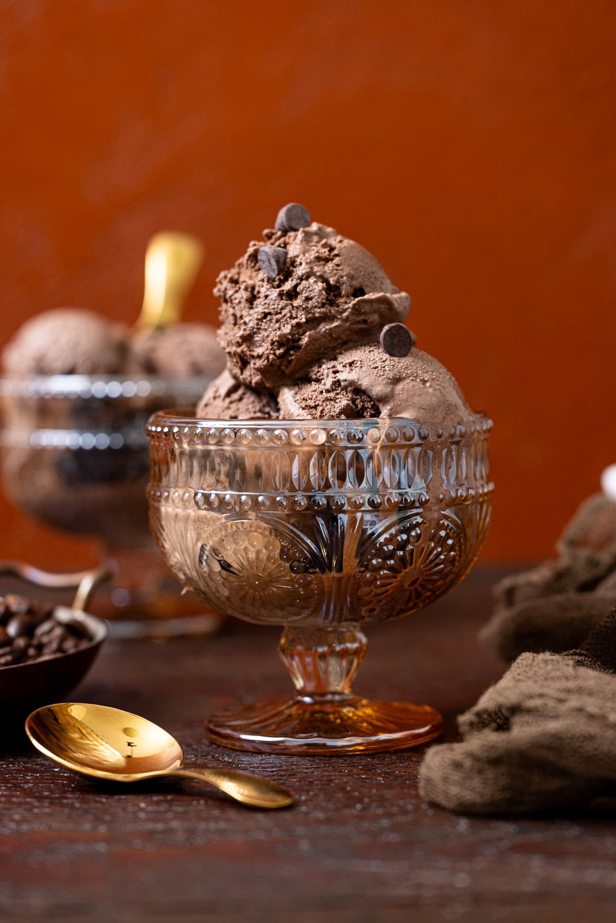 Two bowls of chocolate ice cream with spoons.