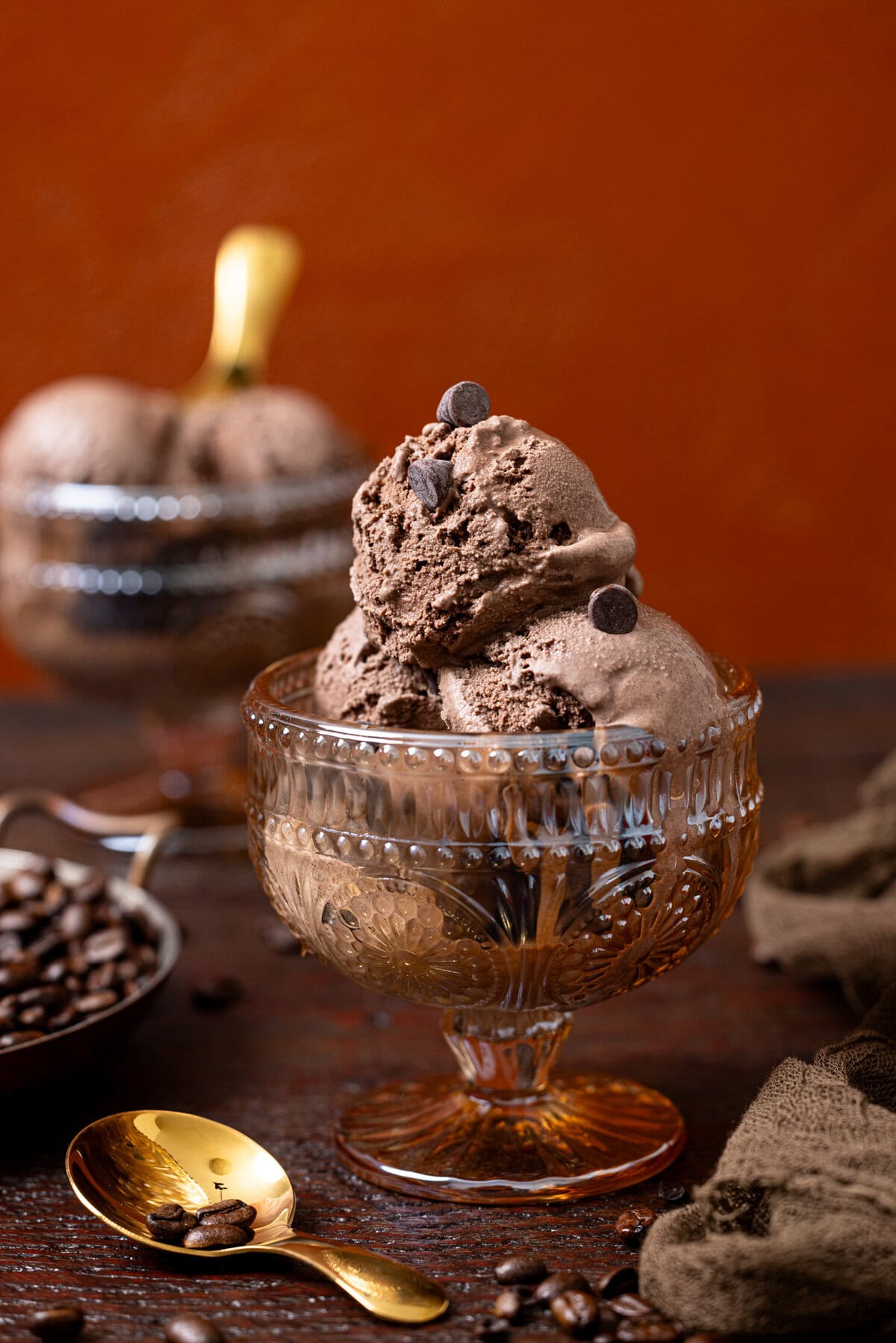 Two bowls of chocolate ice cream with chocolate chips and spoons.