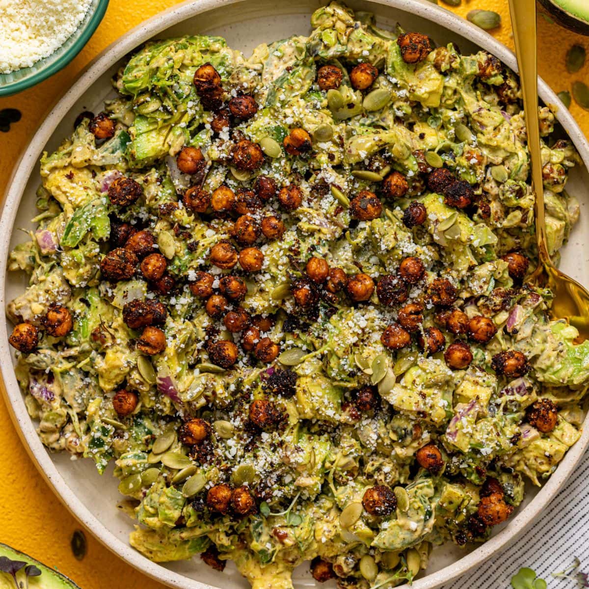 Avocado and chickpea salad in a platter with sauce and ingredients.