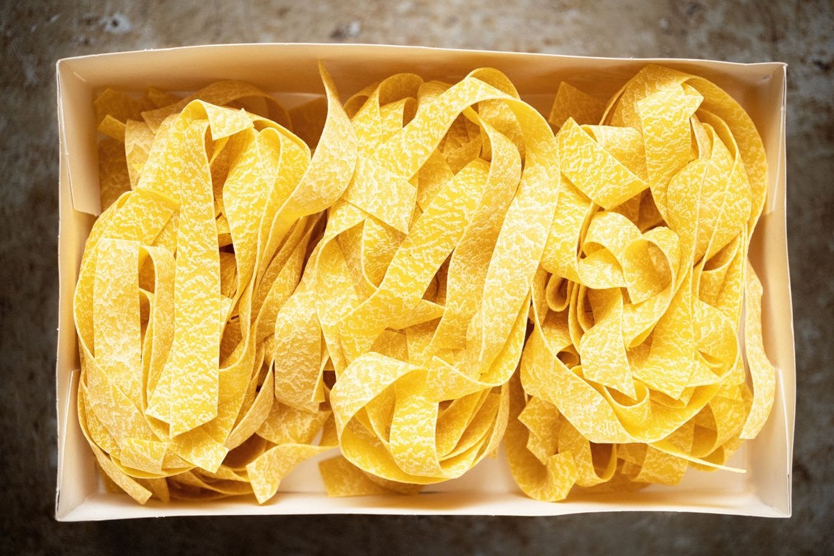 Pappardelle pasta inside a brown paper box.