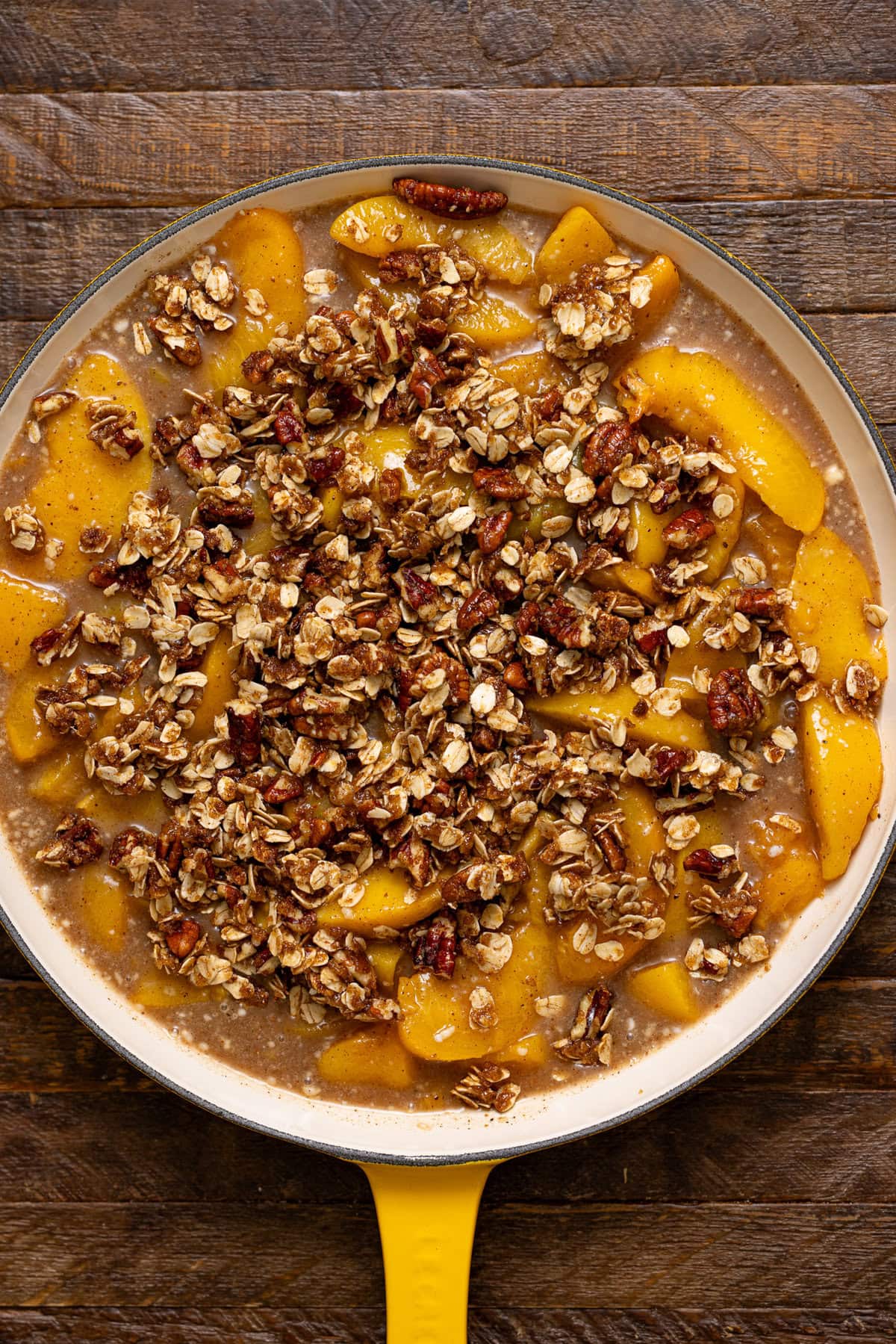 Peach crisp ingredients layered in a skillet.