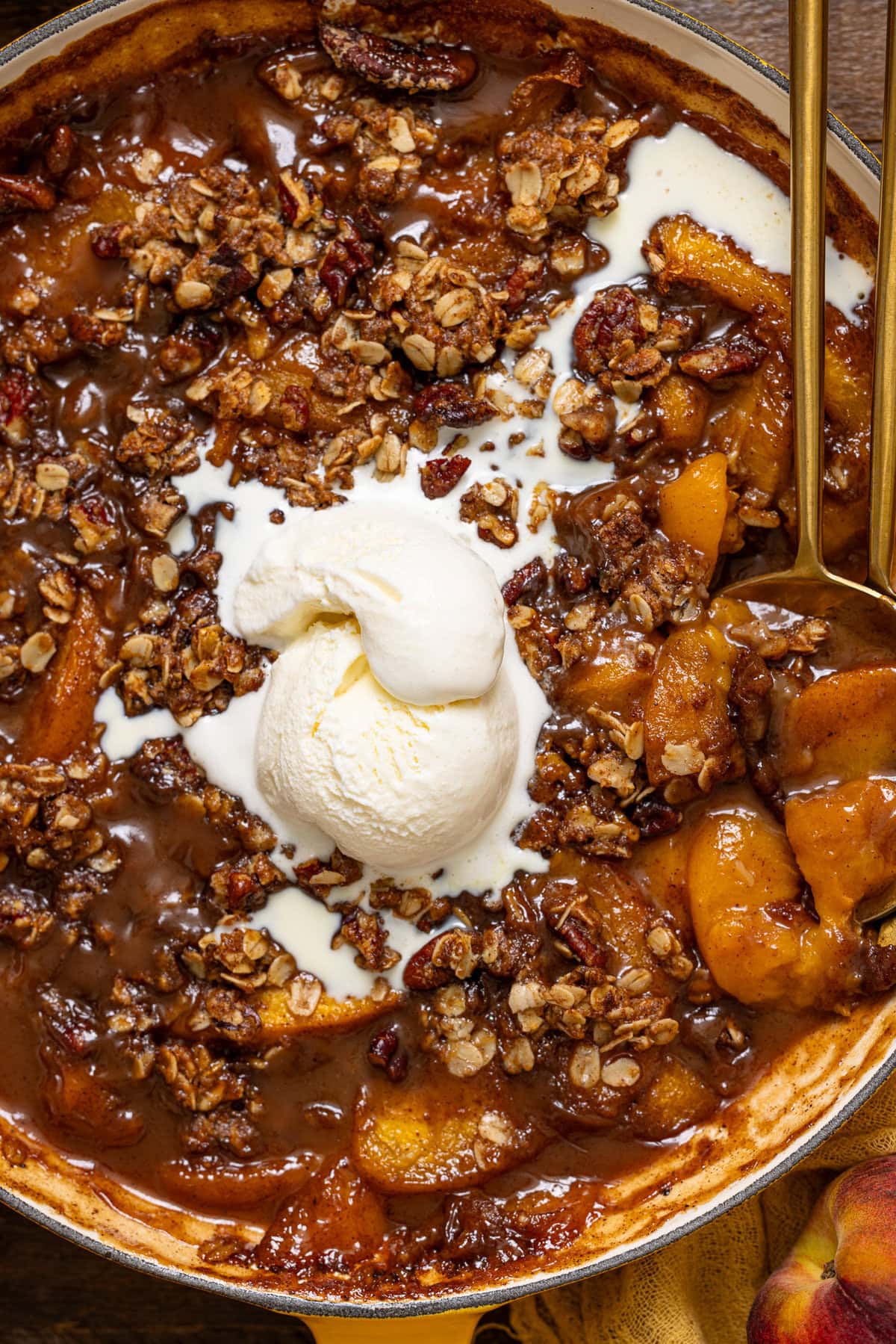 Up close shot of peach crisp with a spoon and ice cream.