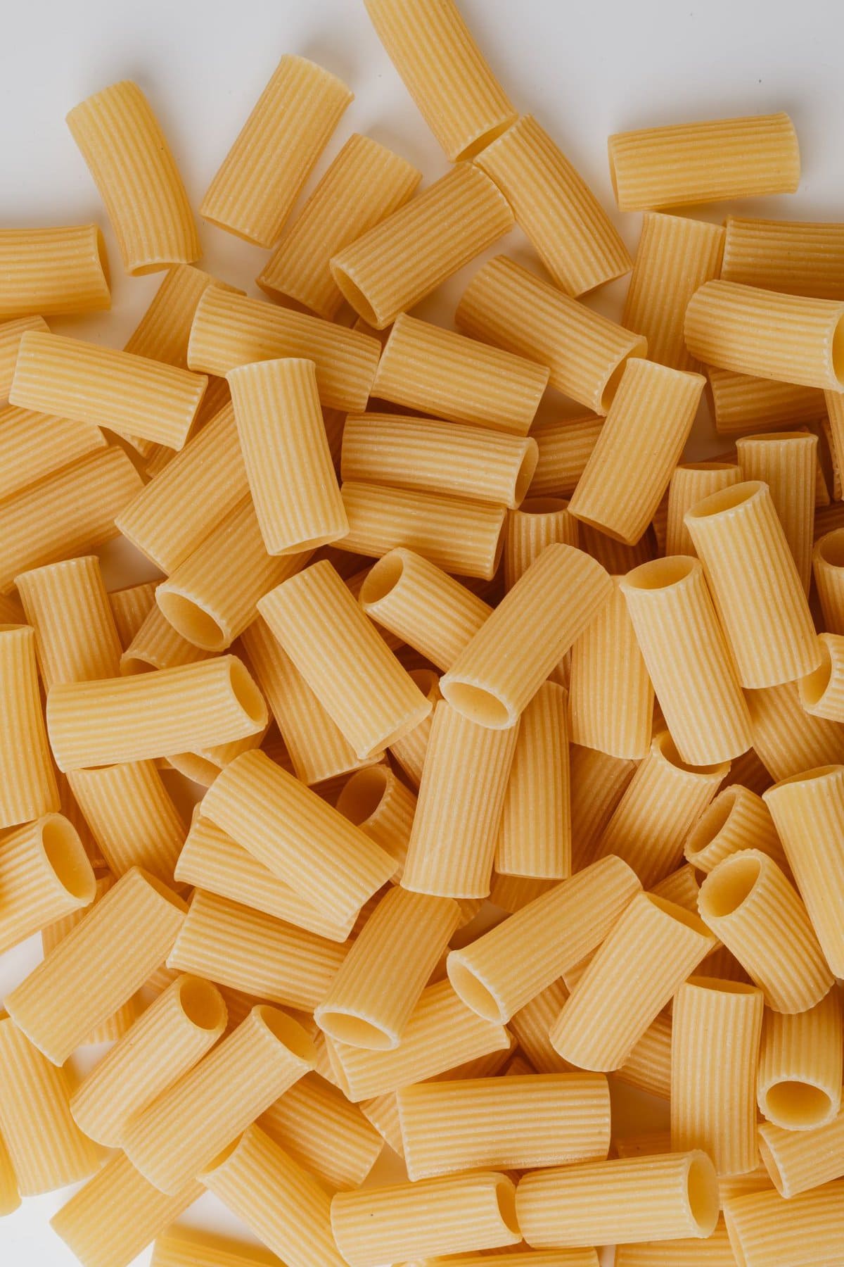 Rigatoni pasta laying on white background.