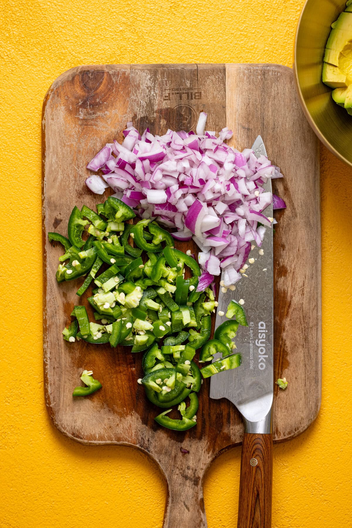 Veggies chopped on a cutting board with a knife. 