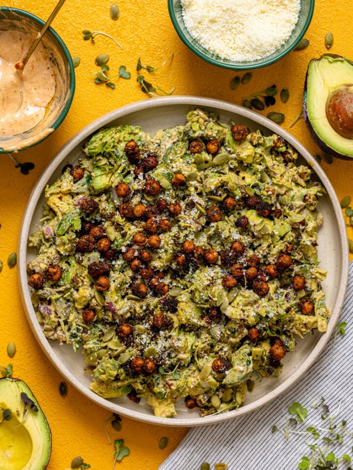 Avocado and chickpea salad in a platter with sauce and ingredients.