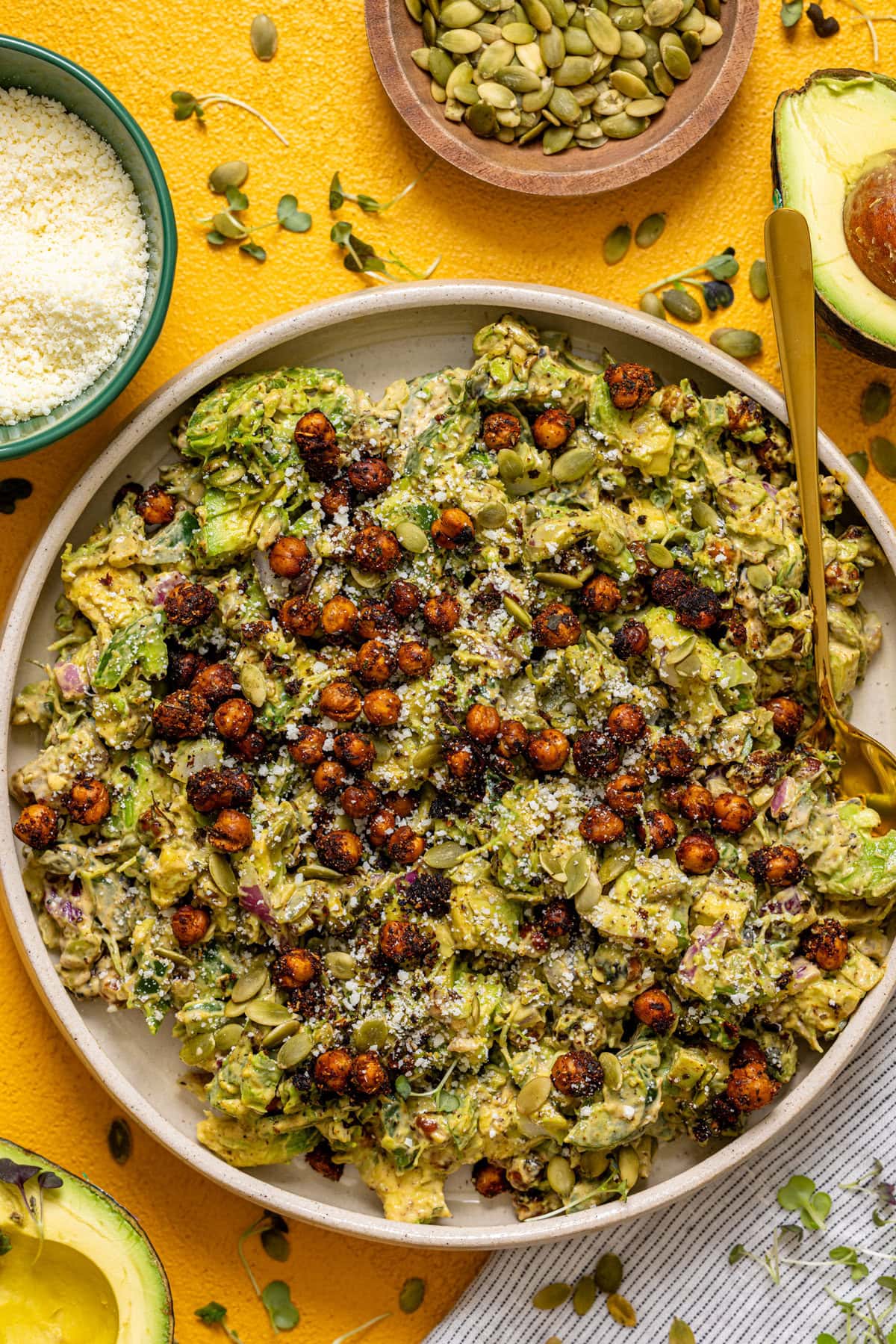 Avocado and chickpea salad in a platter on a yellow table.