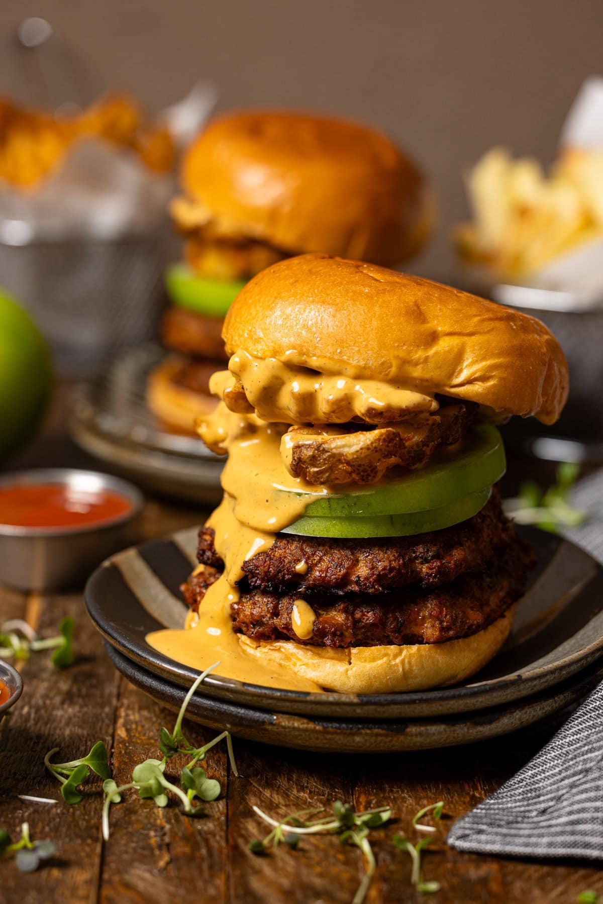 Smashed burgers on a stacked plates with fries.