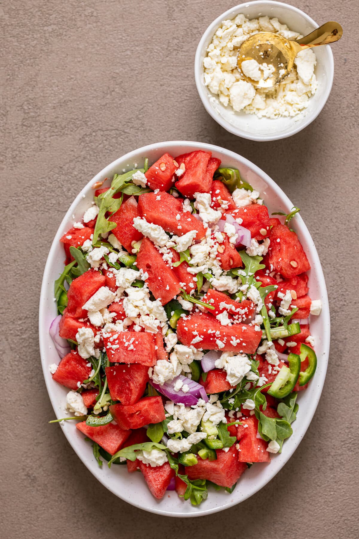 Watermelon salad in a white serving dish with a side of feta cheese.