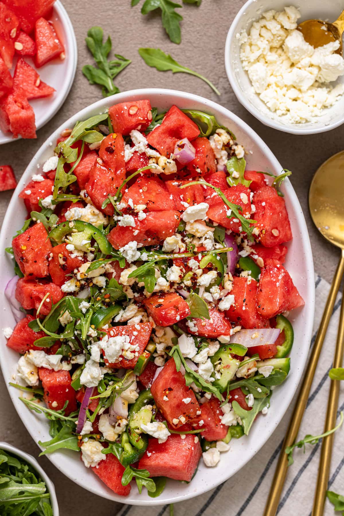 Closer shot of watermelon salad with spoons and feta cheese.