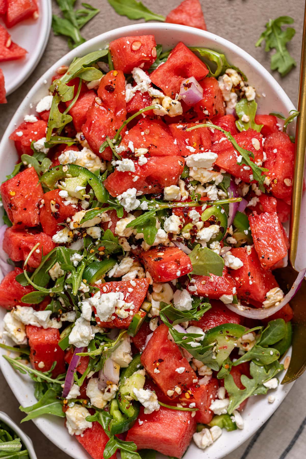 Up close shot of watermelon salad with gold spoon.