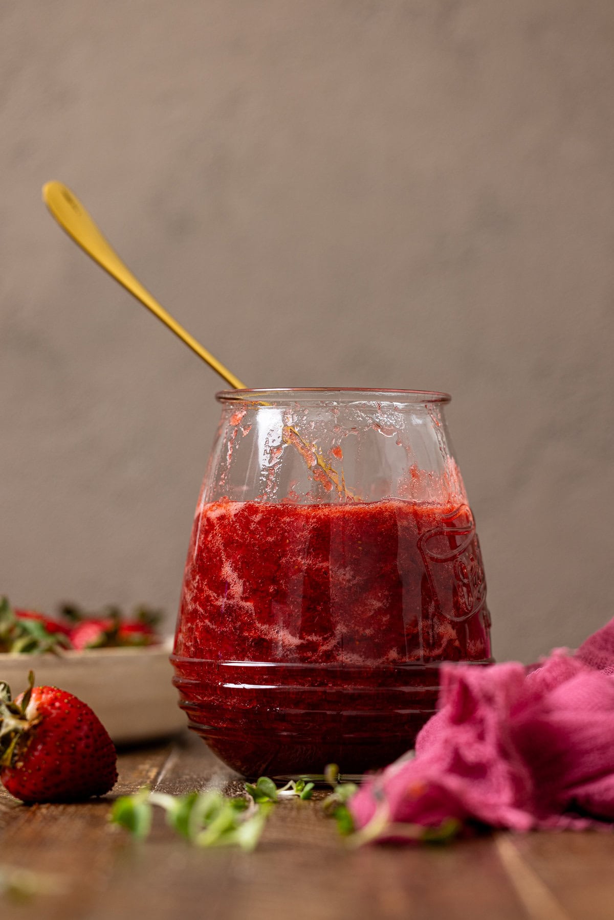 Strawberry jam in a jar with a spoon.