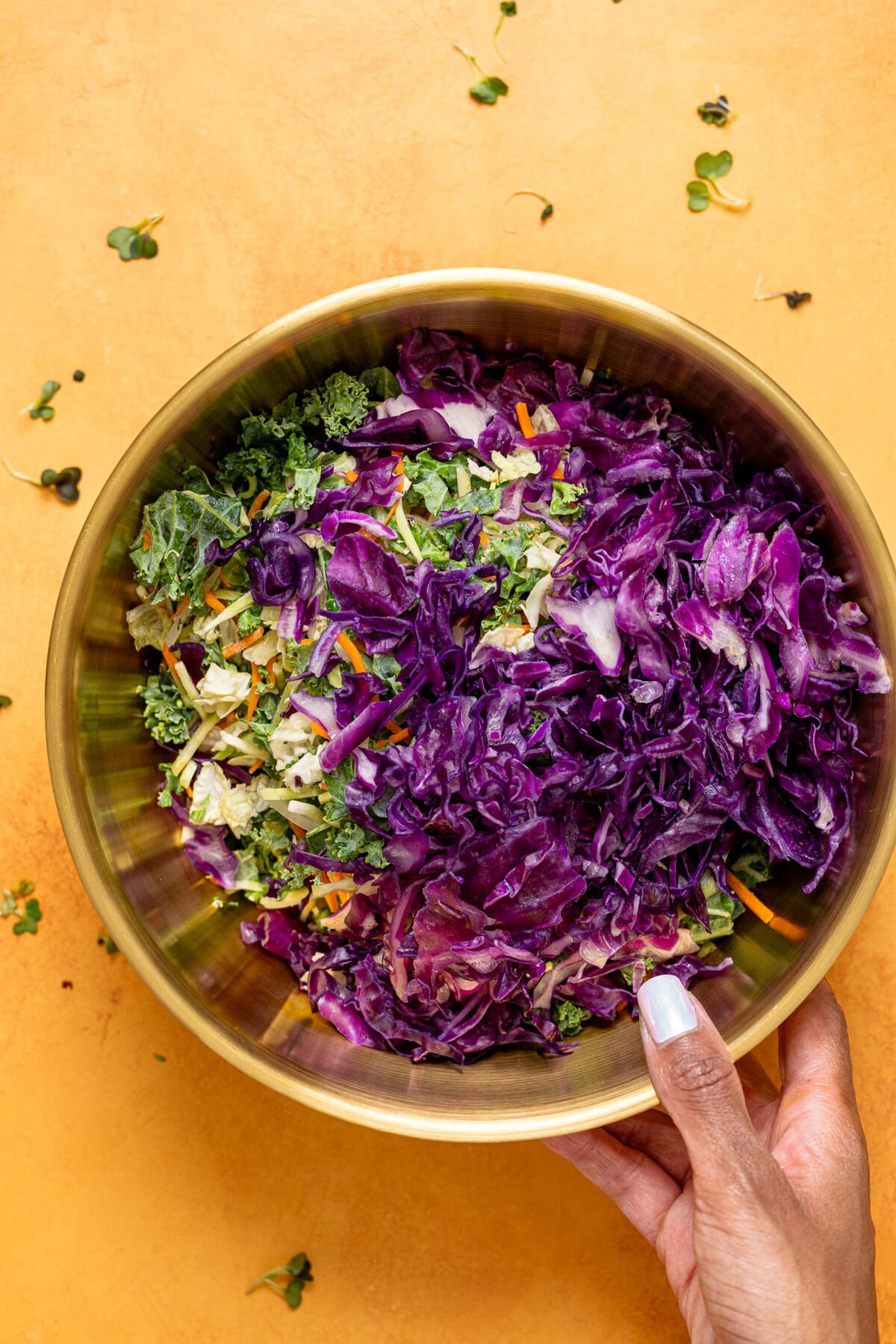 Ingredients in a gold bowl being held.