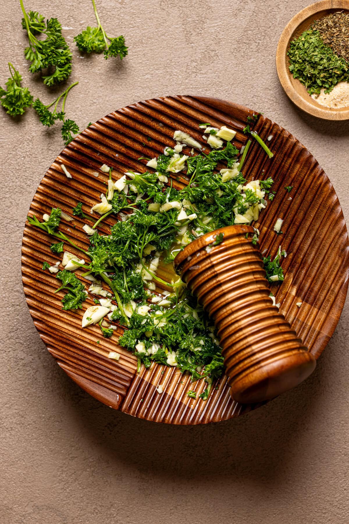 Crushed herbs on a wood  motor and pestal.