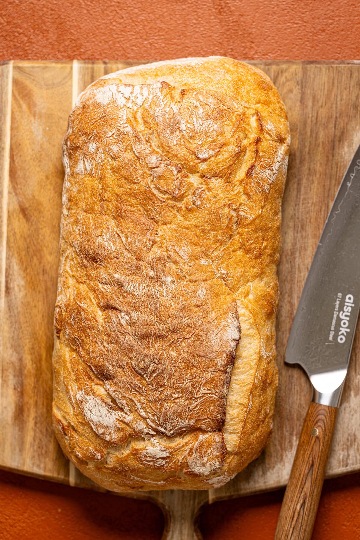 Loaf of rustic bread on a cutting board with a knife. 