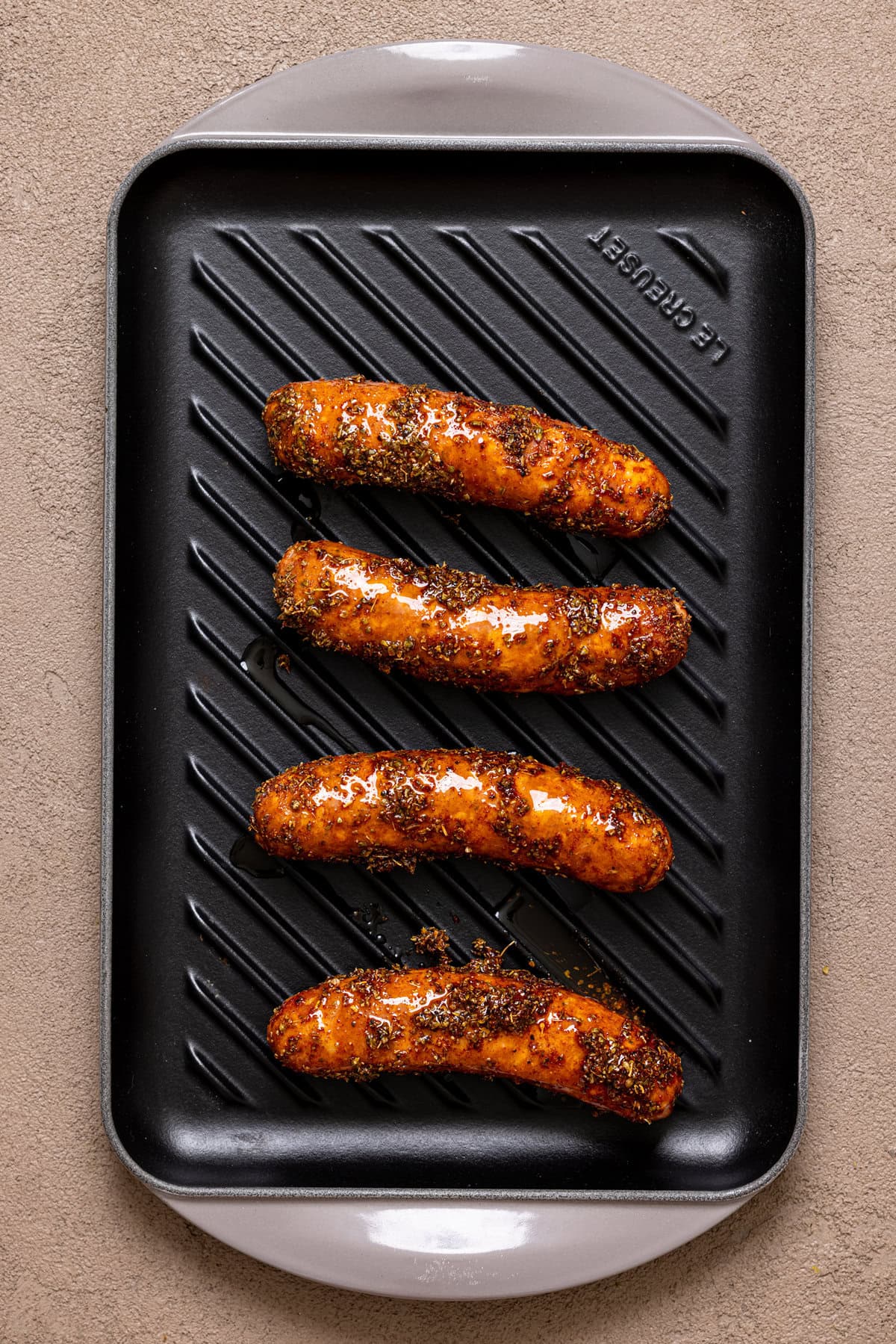 Seasoned sausages lined on a grill pan.