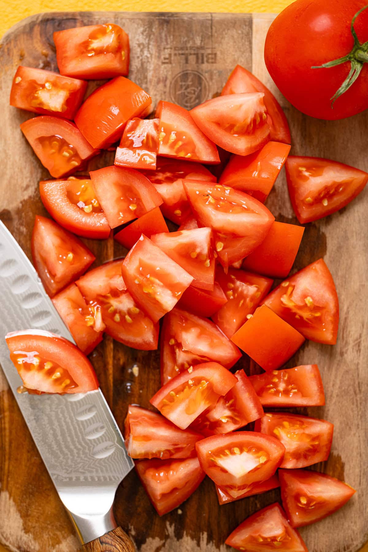 Chopped red tomatoes on a cutting board with a knife.