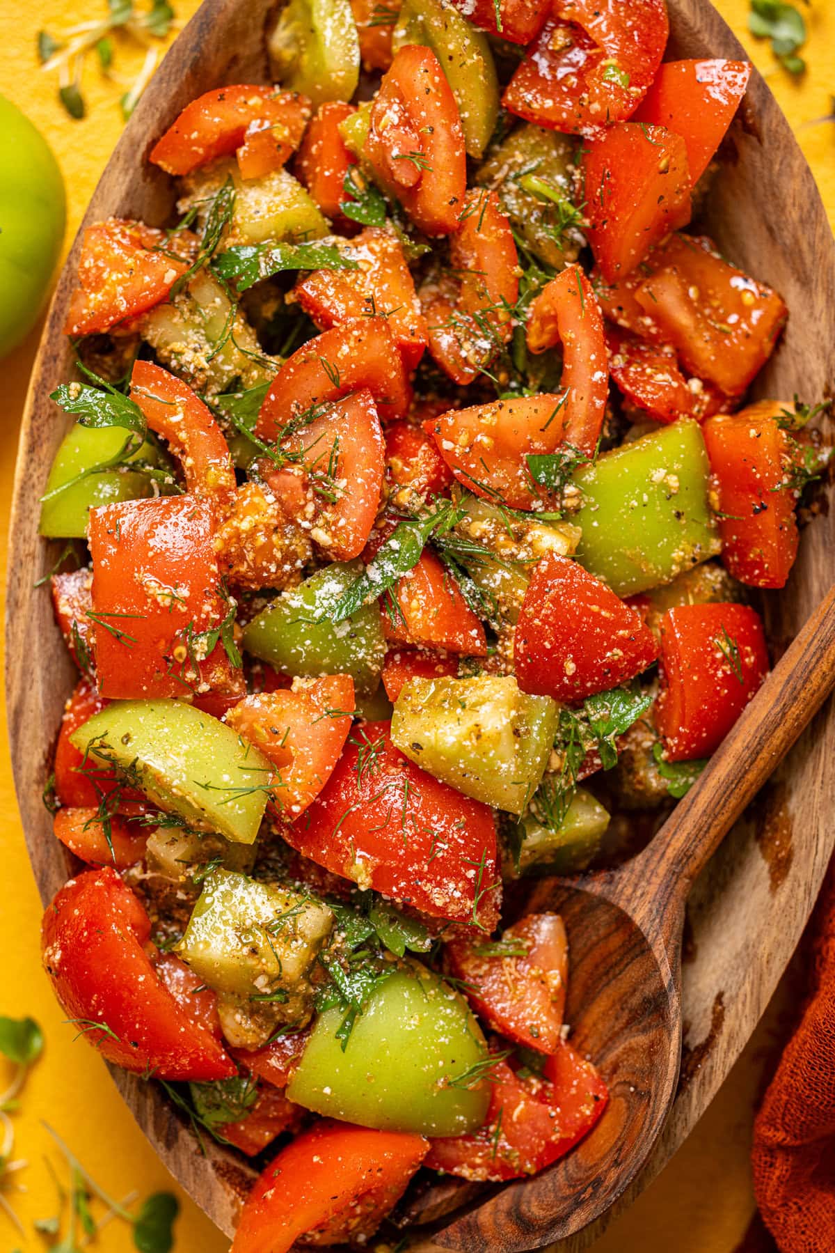 Up close shot of tomato salad with a wooden spoon.